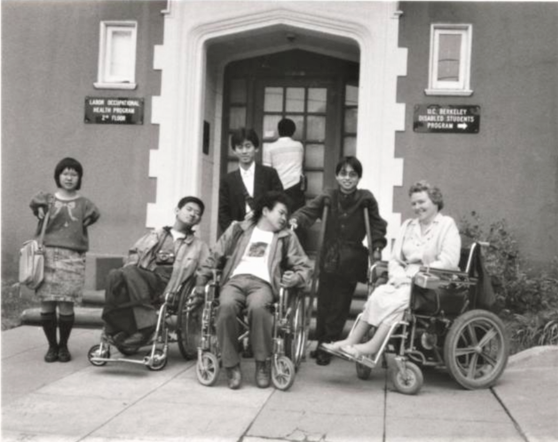 ID: Susan O'Hara and students with disabilities pose in front of Disabled Students Program office