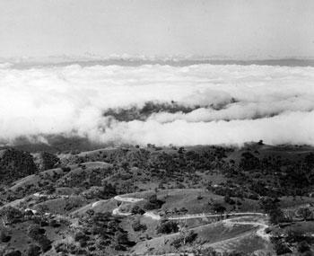  grayscale aerial view of Mount Hamilton with clouds swirling above grassland