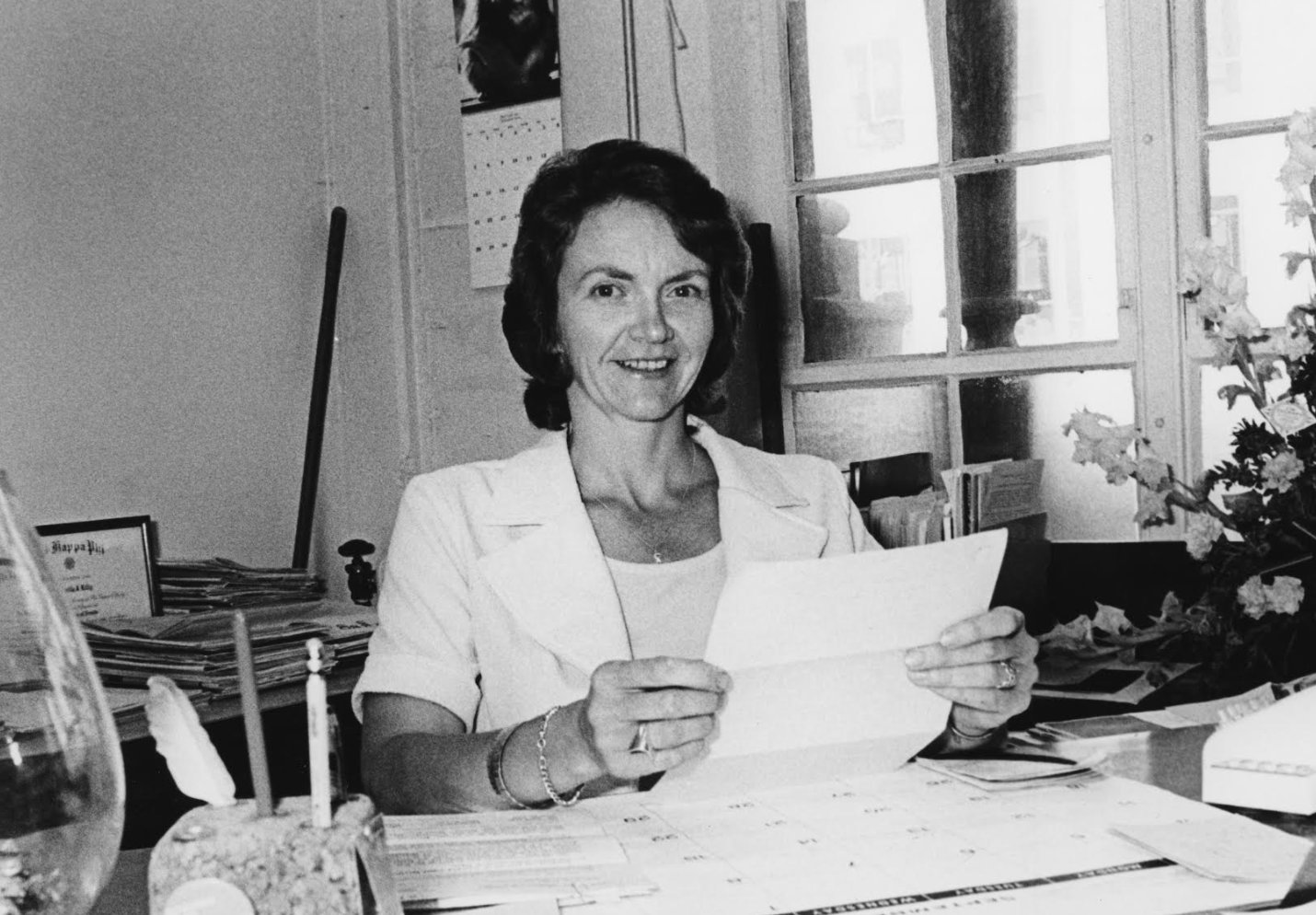 Woman holding letter at desk in black and white