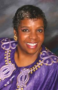  portrait of Diane Howell smiling and dressed in lavender and gold decorated purple top