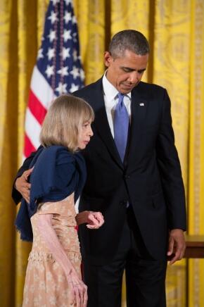  writer and alumna Joan Didion ('56) led onstage by President Barack Obama, against a background of gold curtains and a standing American flag
