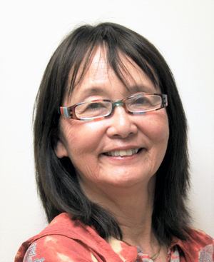  headshot of Evelyn Nakano Glenn smiling in glasses and red floral top against gray background 