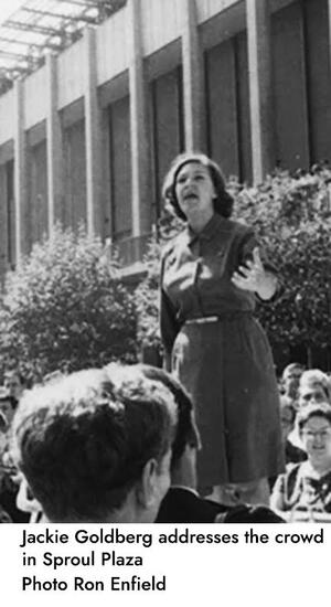  grayscale image of Jackie Goldberg standing on a car and speaking to a crowd; behind her is the east side of thein front of the Martin Luther King Jr. Student Union