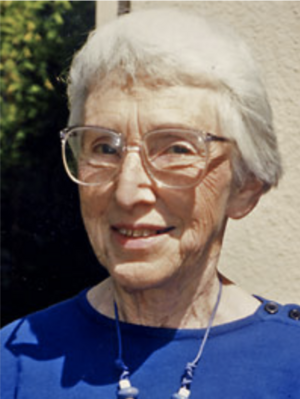 smiling woman with white hair in glasses and navy blue shirt