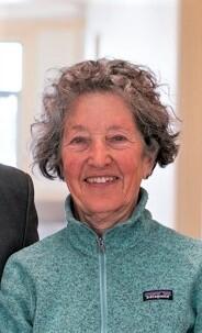  photo of Sally Smith Hughes smiling with short curly hair and teal patagonia jacket